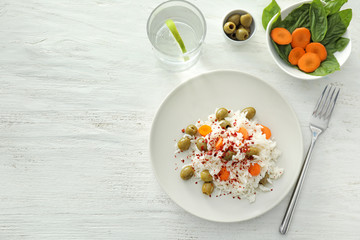 Plate with tasty boiled rice and vegetables on white wooden table