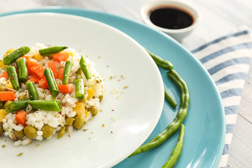Plate with tasty boiled rice and vegetables on table, closeup