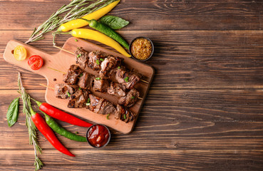 Board with delicious shish kebab and chili pepper on wooden table