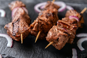 Skewers with delicious shish kebab on slate plate, closeup