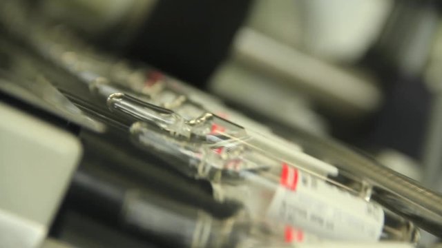 Close up of large batch of labeled medicinal vials being transported on machine.