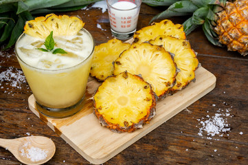 Pineapple juice and pineapple slices cut into pieces on a wooden table. Healthy wood fiber helps to reduce food. Pineapple juice Contains fresh milk, nectar and salt.