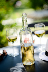 two glass of cool white wine with bottle outdoor in restaurant terrace during a sunny summer day