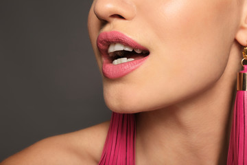 Beautiful young woman with pink lipstick on grey background, closeup