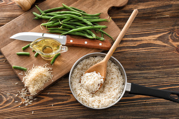 Saucepan with boiled rice on wooden table