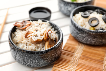 Bowl with tasty boiled rice and mushrooms on light wooden table
