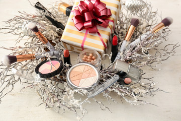 Set of decorative cosmetics with Christmas present and wreath on white wooden table