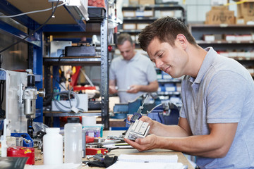 Fototapeta premium Engineer In Factory Measuring Component At Work Bench Using Micrometer