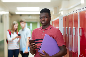 Portrait Of Male High School Student Bullied By Text Message In Corridor