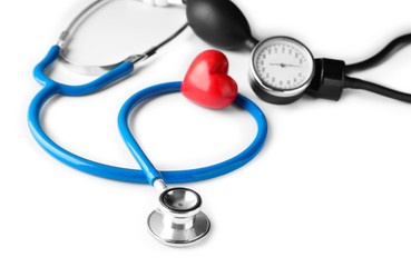 Medical stethoscope, sphygmomanometer and red heart on white background. Cardiology concept