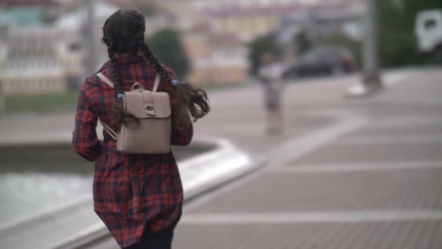 girl with a backpack runs, late for the bus in the evening, back view, slow motion