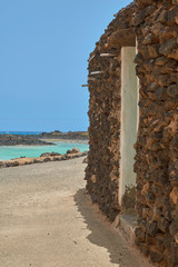 Nice views from a white stone door facing the turquoise sea and mountains within the ocean in Isla de Lobos, Fuerteventura, Canary Islands, Spain