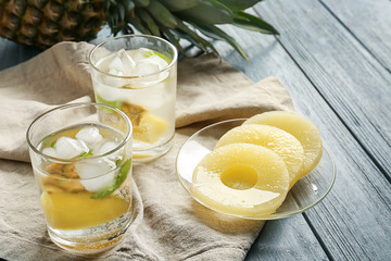 Tasty drink with ice and pineapple in glasses on wooden table