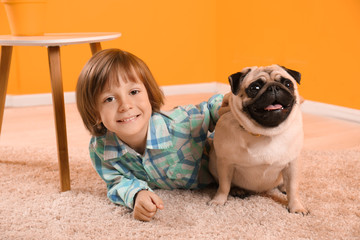 Little boy lying with cute pug dog on floor at home © Pixel-Shot