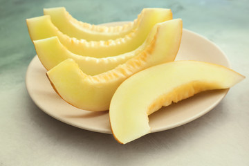Plate with slices of ripe melon on light background