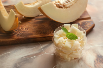 Jar with tasty melon cubes on color table