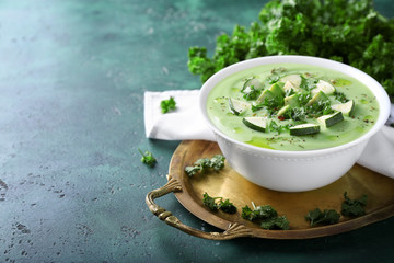 Bowl with delicious zucchini soup on green table
