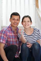 Obraz premium Portrait Of Young Couple Sitting On Stairs Holding Keys To New Home