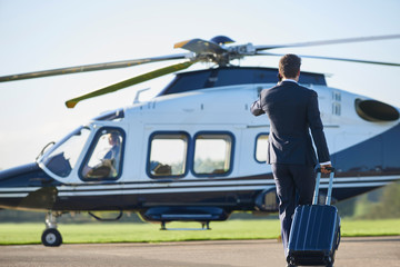 Rear View Of Businessman Walking Towards Helicopter Whilst Talking On Mobile Phone © highwaystarz