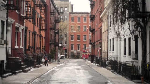 Looking down a thin urban street at snow covered stoops on a cold brisk winter day.