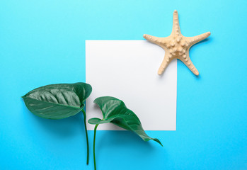 Fresh tropical leaves, starfish and blank card on color background