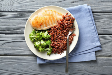 Tasty boiled red rice with meat and broccoli on grey table