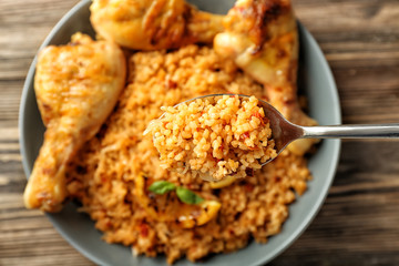 Spoon with tasty boiled rice over plate, closeup