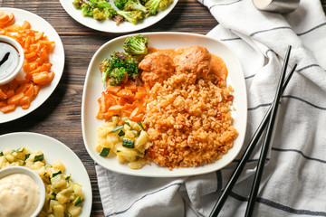 Tasty boiled rice with meatballs, vegetables and sauces on wooden table