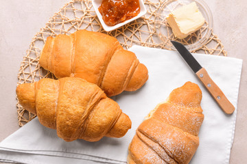 Tasty croissants with jam and butter on grey background