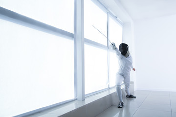 Young female fencer training in gym