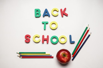 Words BACK TO SCHOOL made of color letters with apple and pencils on white background