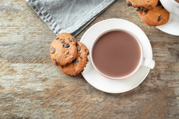 Cup of delicious cocoa and cookies on wooden table