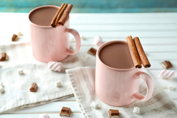 Cups of delicious cocoa and sweets on white table