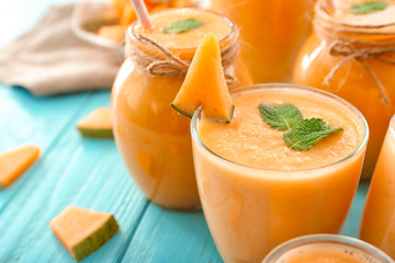 Glass and jars with tasty melon smoothie on color table