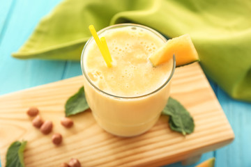 Glass with tasty melon smoothie on wooden board
