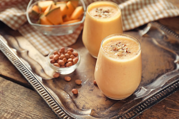 Glasses with tasty melon smoothie and peanuts on metal tray