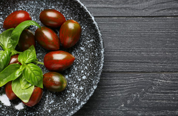Plate with delicious tomatoes and fresh basil on wooden table