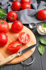 Board with delicious tomatoes on wooden table