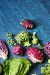 Different types of cabbage on color wooden background