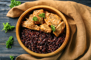 Bowl with tasty boiled rice and meat on wooden table
