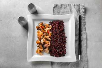 Plate with tasty boiled rice and seafood on light background