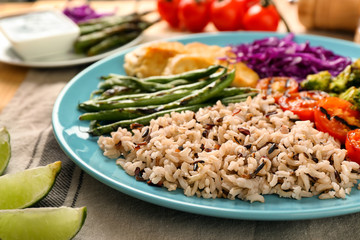 Plate with boiled rice, vegetables and meat on table, closeup
