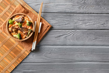 Bowl with boiled rice, meat and broccoli on grey table