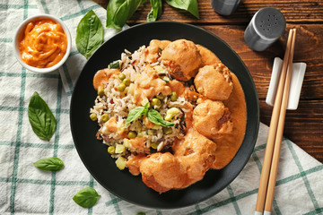 Plate with boiled rice, vegetables and meatballs on table
