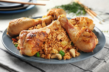 Plate with boiled rice, chicken legs and vegetables on table