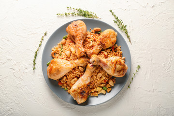 Plate with boiled rice, chicken legs and vegetables on white table