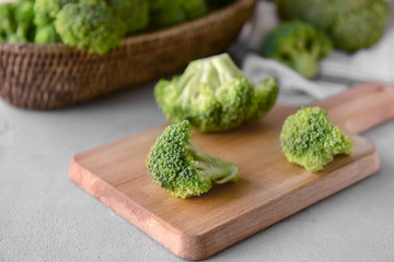 Board with fresh green broccoli on grey table