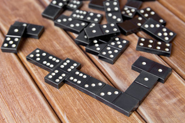 Black old, vintage dominoes on a wooden table closeup. The concept of the game dominoes.