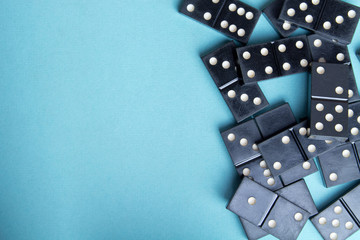 Black old, vintage dominoes on a  cardboard turquoise background. The concept of the game dominoes. Selective focus