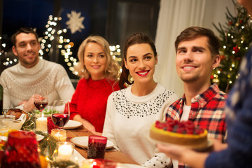 holidays and celebration concept - happy friends having christmas dinner at home